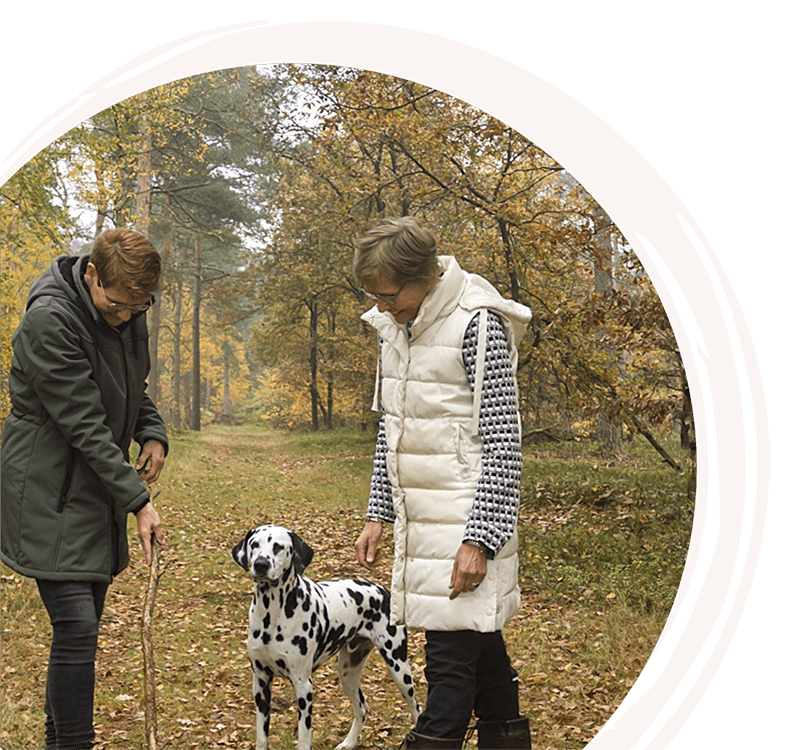 Saskia wandelt met een cliënt en een dalmatiër door het bos