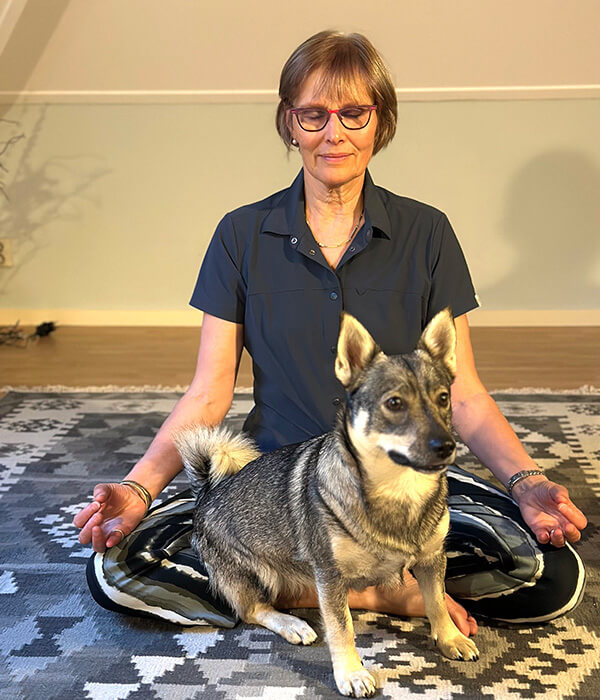 Saskia mediteert op een yogamat met haar hond